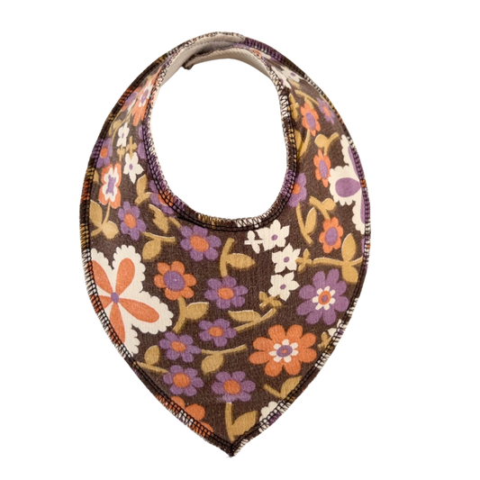 dregglis sydd i ett brunt återbrukat tyg med blommor i lila, orange, grönt och vitt.